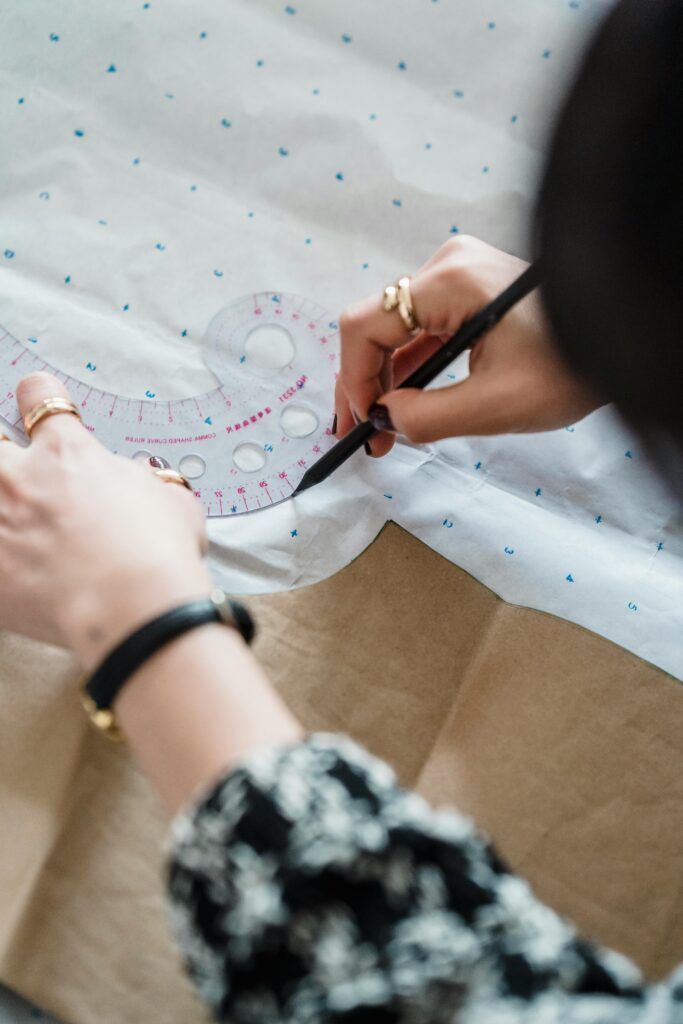 Close-up of a tailor tracing a sewing pattern on fabric with precise tools.